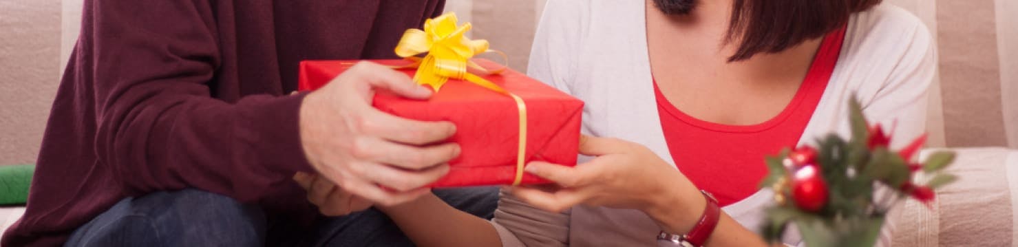 A man handing his partner a wrapped gift.