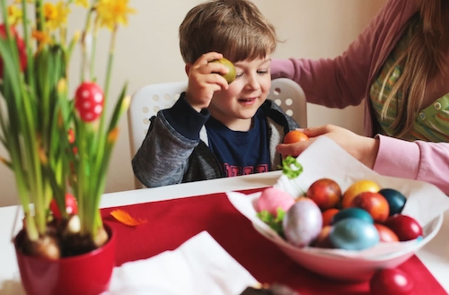 A boy holding an Easter egg at a table.